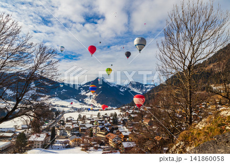 Colorful hot air balloons flying over the winter village of Chateau-d'Oex during the International Balloon Festival in the Swiss Alps, Switzerland Colorful hot air balloons flying over the winter village of Chateau-d'Oex during the International Balloon Festival in the Swiss Alps, Switzerland 141860058