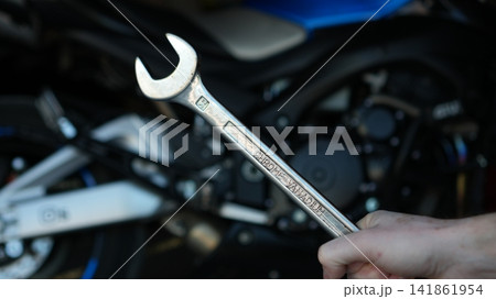Closeup Hands Holding Wrench, Motorcycle Engine, Gritty Roadside Repair Scene With Oil Smudges, Focused Finger Closeup Hands Holding Wrench, Motorcycle Engine, Gritty Roadside Repair Scene With Oil Smudges, Focused Finger 141861954