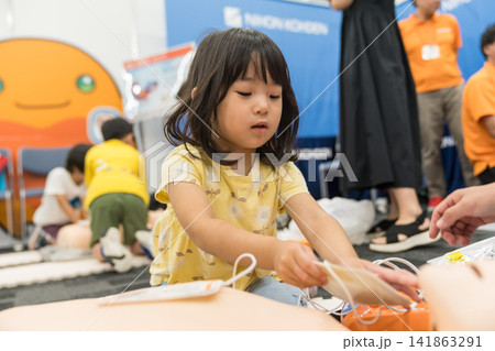 救急救命体験イベントでAEDに触れる日本人の女の子の幼児 救急救命体験イベントでAEDに触れる日本人の女の子の幼児 141863291