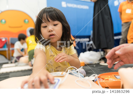 救急救命体験イベントでAEDに触れる日本人の女の子の幼児 救急救命体験イベントでAEDに触れる日本人の女の子の幼児 141863296