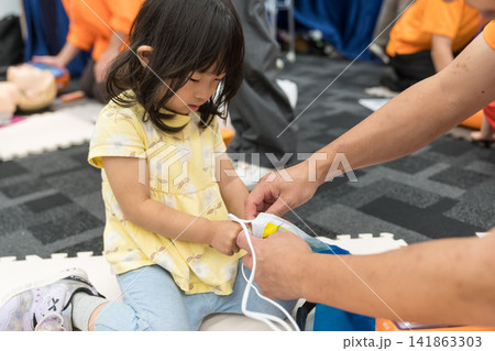 救急救命体験イベントでAEDに触れる日本人の女の子の幼児 救急救命体験イベントでAEDに触れる日本人の女の子の幼児 141863303