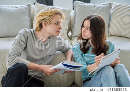 Young students studying together, looking at each other, confused. 141863958