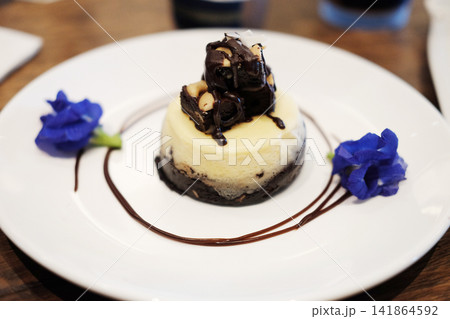 Fresh mini chocolate cheesecake with edible flowers in white plate 141864592