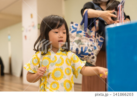 ひまわり柄の甚平を着ておもちゃのハンマーでゲームをする日本人の女の子の幼児 ひまわり柄の甚平を着ておもちゃのハンマーでゲームをする日本人の女の子の幼児 141866203
