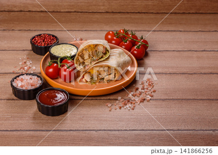 Grilled chicken shawarma or doner with tomatoes, cucumber, and sauces, takeout food Grilled chicken shawarma or doner with tomatoes, cucumber, and sauces, takeout food 141866256