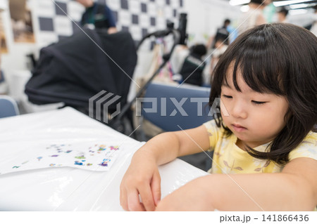 ワークショップでシールを使った工作に集中する日本人の女の子の幼児 ワークショップでシールを使った工作に集中する日本人の女の子の幼児 141866436