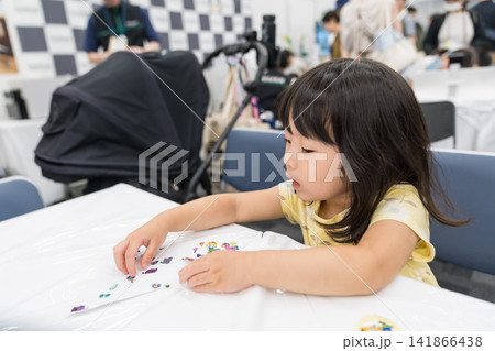 ワークショップでシールを使った工作に集中する日本人の女の子の幼児 ワークショップでシールを使った工作に集中する日本人の女の子の幼児 141866438