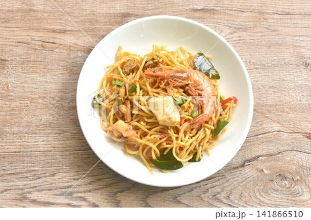 spicy stir fried spaghetti seafood slice squid and shrimp couple clam with chili and basil leaf in Thai tom yum sauce on plate spicy stir fried spaghetti seafood slice squid and shrimp couple clam with chili and basil leaf in Thai tom yum sauce on plate 141866510