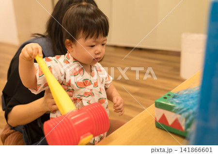 スイカ柄の甚平を着たおもちゃのハンマーで遊ぶ日本人の男の赤ちゃん スイカ柄の甚平を着たおもちゃのハンマーで遊ぶ日本人の男の赤ちゃん 141866601