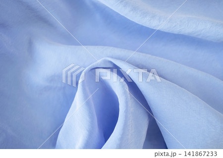 Blue silk fabric with soft folds and waves. Soft blue silk fabric background. Light satin textile, natural fabric. Blue silk fabric with soft folds and waves. Soft blue silk fabric background. Light satin textile, natural fabric. 141867233