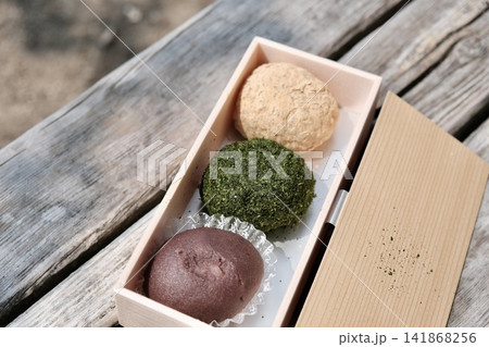 屋外の木製ベンチに置かれた、折箱に美しく並ぶ上品な3色の手作りおはぎ 屋外の木製ベンチに置かれた、折箱に美しく並ぶ上品な3色の手作りおはぎ 141868256