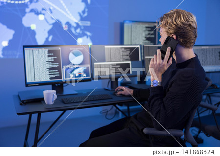 Cybersecurity engineer monitoring threats on a workstation with multiple screens Cybersecurity engineer monitoring threats on a workstation with multiple screens 141868324