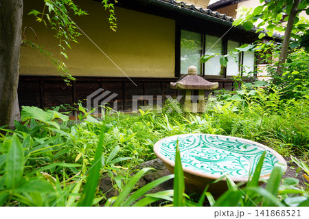 新緑の日本庭園に佇む唐草模様の美しい水鉢と灯篭の風景 新緑の日本庭園に佇む唐草模様の美しい水鉢と灯篭の風景 141868521