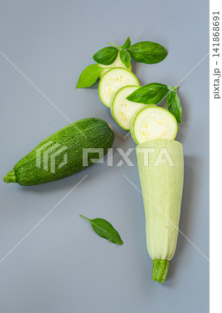Fresh zucchini with sliced courgette on gray background with basil Fresh zucchini with sliced courgette on gray background with basil 141868691
