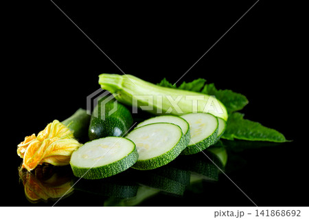 Fresh summer squash with green leaves on black reflective surface Fresh summer squash with green leaves on black reflective surface 141868692