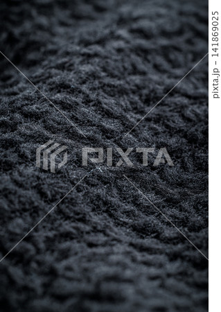 The texture of a soft black fleece fabric with visible fibers and folds The texture of a soft black fleece fabric with visible fibers and folds 141869025