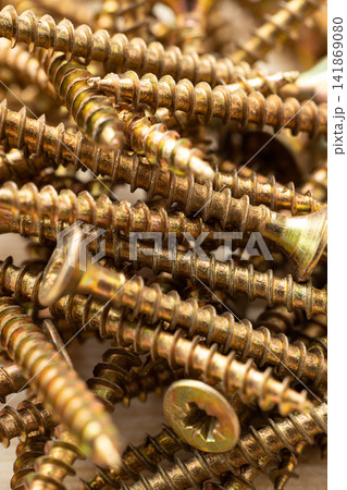 A close-up of a pile of wooden screws with gold-colored heads, scattered randomly on a background A close-up of a pile of wooden screws with gold-colored heads, scattered randomly on a background 141869080