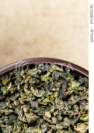 Top view closeup dark wood cup full of loose tea on natural fabric Top view closeup dark wood cup full of loose tea on natural fabric 141869236