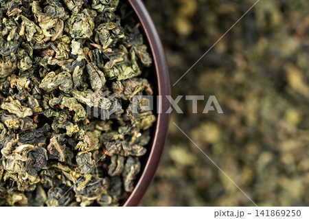 Wooden cup full of green oolong surrounded by loose tea texture Wooden cup full of green oolong surrounded by loose tea texture 141869250