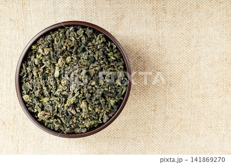 Top view closeup dark wood cup full of loose tea on natural fabric Top view closeup dark wood cup full of loose tea on natural fabric 141869270