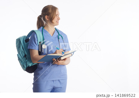 Aspiring Nurse with Notebook and Backpack Looking Aside Aspiring Nurse with Notebook and Backpack Looking Aside 141869522