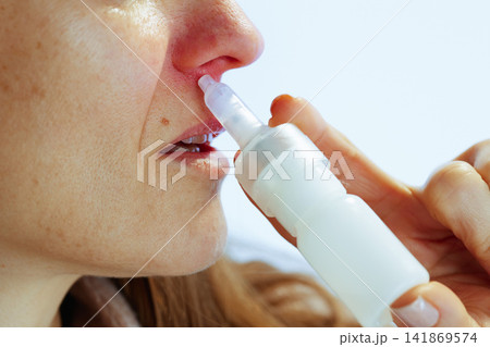 Woman Administering Nasal Spray for Allergy Relief Woman Administering Nasal Spray for Allergy Relief 141869574