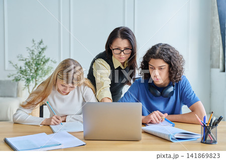 Two smiling teen students with laptop at desk Two smiling teen students with laptop at desk 141869823
