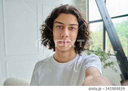 Happy teen boy taking selfie in a bright room Happy teen boy taking selfie in a bright room 141869839