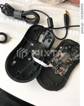 Disassembled black computer mouse showing internal circuit board and cable. 141869939