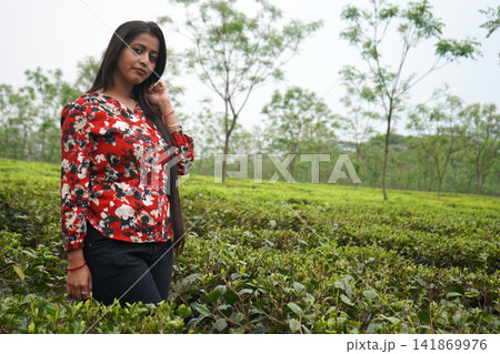Beautiful Indian woman posing amidst a lush green tea garden plantation in North Bengal Beautiful Indian woman posing amidst a lush green tea garden plantation in North Bengal 141869976