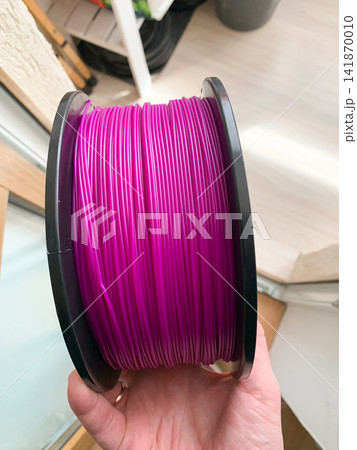 Bright pink 3D printing filament spool held in a hand for project creation 141870010