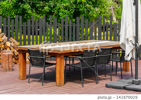 Modern outdoor dining table and chairs on backyard patio terrace, place to relax for group of people Modern outdoor dining table and chairs on backyard patio terrace, place to relax for group of people 141870029