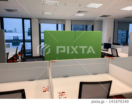 The interior of a contemporary office space with empty desks and a green privacy partition under bright ceiling lights The interior of a contemporary office space with empty desks and a green privacy partition under bright ceiling lights 141870140