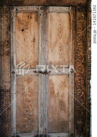 Rustic carved wooden door with traditional decorative details and aged texture Rustic carved wooden door with traditional decorative details and aged texture 141871362