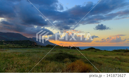 Scenic coastal valley with rolling hills and dramatic sunset clouds over the sea 141871627
