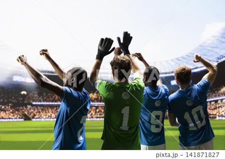 Soccer players facing stadium stands from behind and waving to fans, raised arms to greet supporters before football match. Teammates in blue and green jersey, goalkeeper captain. Soccer players facing stadium stands from behind and waving to fans, raised arms to greet supporters before football match. Teammates in blue and green jersey, goalkeeper captain. 141871827