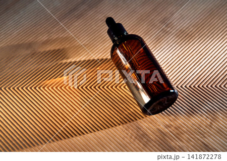 Amber dropper bottle holding skincare oil on textured background Amber dropper bottle holding skincare oil on textured background 141872278