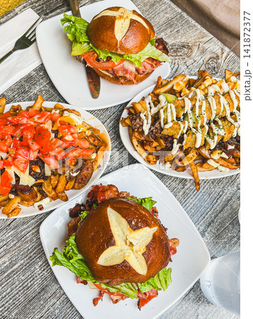 Gourmet Pretzel Bun Burgers and Loaded Canadian Poutine Fries Flat Lay Gourmet Pretzel Bun Burgers and Loaded Canadian Poutine Fries Flat Lay 141872377