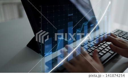 Hands typing on a keyboard with digital financial graphs showing trends on a screen in a modern office setting, symbolizing data analysis and investment growth Copula 141874254