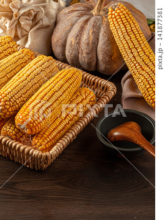 dried yellow corn cobs arranged in a woven basket 141877381