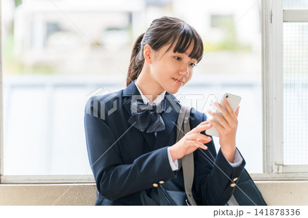 校舎の廊下でスマホを使う笑顔の中学生,高校生の女の子(防犯,安全,安心) 校舎の廊下でスマホを使う笑顔の中学生,高校生の女の子(防犯,安全,安心) 141878336