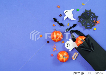 Halloween shopping bag filled with pumpkins ghosts and candy on purple background Halloween shopping bag filled with pumpkins ghosts and candy on purple background 141878587