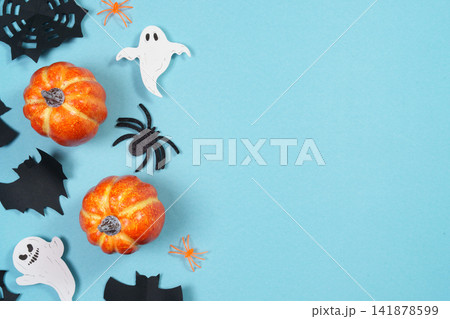 Halloween flat lay concept with pumpkins ghosts bats and spiders on blue background with copy space Halloween flat lay concept with pumpkins ghosts bats and spiders on blue background with copy space 141878599