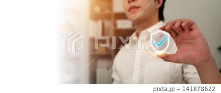 Man holding virtual shield icon with checkmark for security and protection Man holding virtual shield icon with checkmark for security and protection 141878622