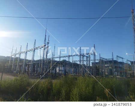 A complex urban electrical substation view with steel lattice structures, transformers, and intricate overhead lines. A complex urban electrical substation view with steel lattice structures, transformers, and intricate overhead lines. 141879053