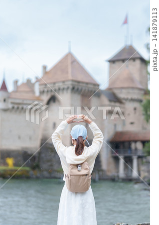Woman Tourist Explore Chateau de Chillon, Montreux, Switzerland in Summer. Traveler Making Heart Shape at Castle on Lake Geneva, Famous European Tourist Attraction and Europe Travel Destination Woman Tourist Explore Chateau de Chillon, Montreux, Switzerland in Summer. Traveler Making Heart Shape at Castle on Lake Geneva, Famous European Tourist Attraction and Europe Travel Destination 141879113