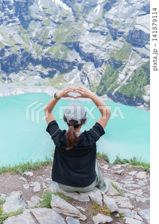 Woman Tourist Explore Oeschinensee, Kandersteg, Switzerland in Summer. Hiker Making Heart Shape at Turquoise Alpine Lake and Hiking Trail View, Popular Europe Tourist Attraction and Travel Destination Woman Tourist Explore Oeschinensee, Kandersteg, Switzerland in Summer. Hiker Making Heart Shape at Turquoise Alpine Lake and Hiking Trail View, Popular Europe Tourist Attraction and Travel Destination 141879114
