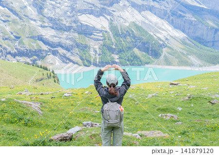 Woman Tourist Explore Oeschinensee, Kandersteg, Switzerland in Summer. Hiker Making Heart Shape at Hiking Trail, Wildflowers and Turquoise Alpine Lake, Popular Europe travel Attraction and Destination Woman Tourist Explore Oeschinensee, Kandersteg, Switzerland in Summer. Hiker Making Heart Shape at Hiking Trail, Wildflowers and Turquoise Alpine Lake, Popular Europe travel Attraction and Destination 141879120