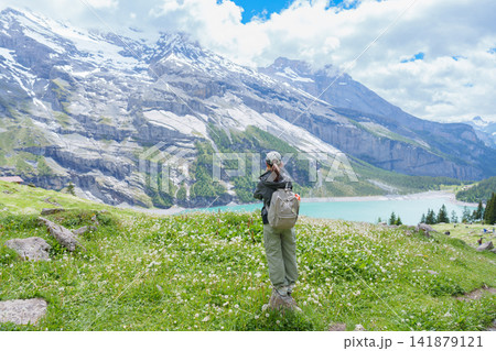 Woman Tourist Explore Oeschinensee, Kandersteg, Switzerland in Summer. Hiker Taking Photo with Smartphone at Hiking Trail, Wildflowers and Turquoise Alpine Lake. Europe travel and Destination Woman Tourist Explore Oeschinensee, Kandersteg, Switzerland in Summer. Hiker Taking Photo with Smartphone at Hiking Trail, Wildflowers and Turquoise Alpine Lake. Europe travel and Destination 141879121