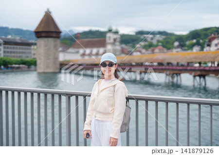Woman Tourist Explore Lucerne, Switzerland in Summer. Traveler Visit Chapel Bridge and Water Tower on Reuss River. Famous European Landmark, Popular Tourist Attraction and Travel Destination in Europe Woman Tourist Explore Lucerne, Switzerland in Summer. Traveler Visit Chapel Bridge and Water Tower on Reuss River. Famous European Landmark, Popular Tourist Attraction and Travel Destination in Europe 141879126